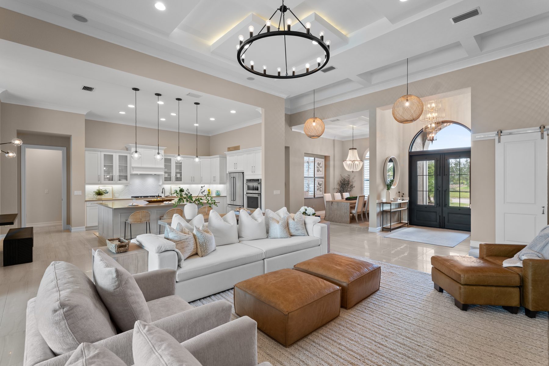 Great room with chandelier, kitchen, and arched front doors